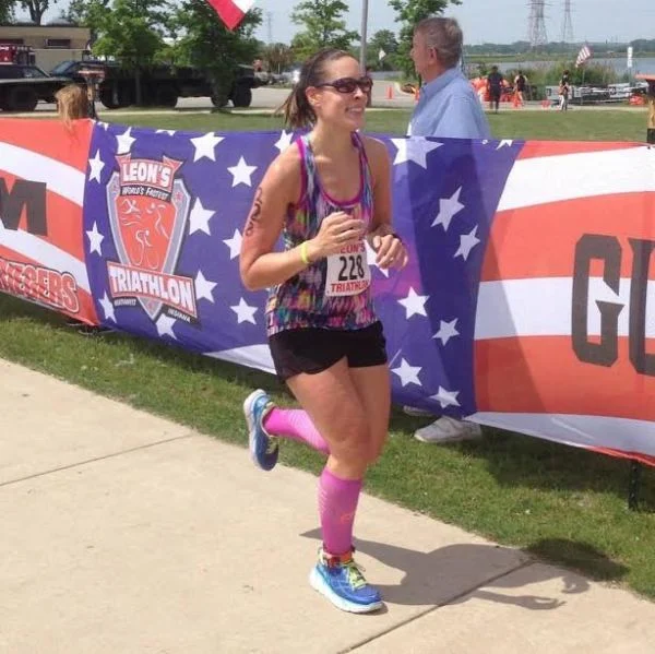 Kim crossing a triathlon finish line.
